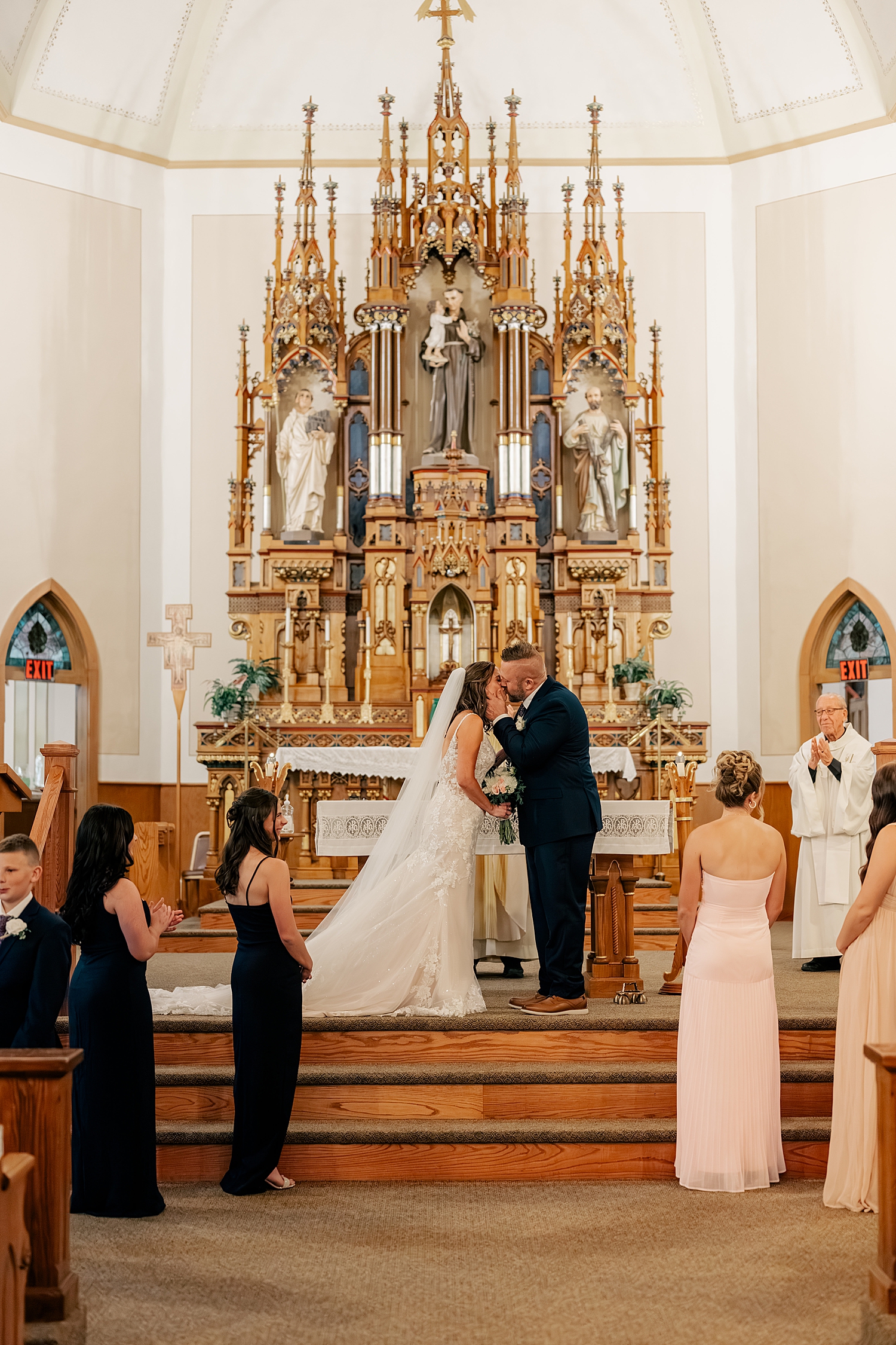 newlyweds share first kiss at alter in catholic church by Minnesota wedding photographer