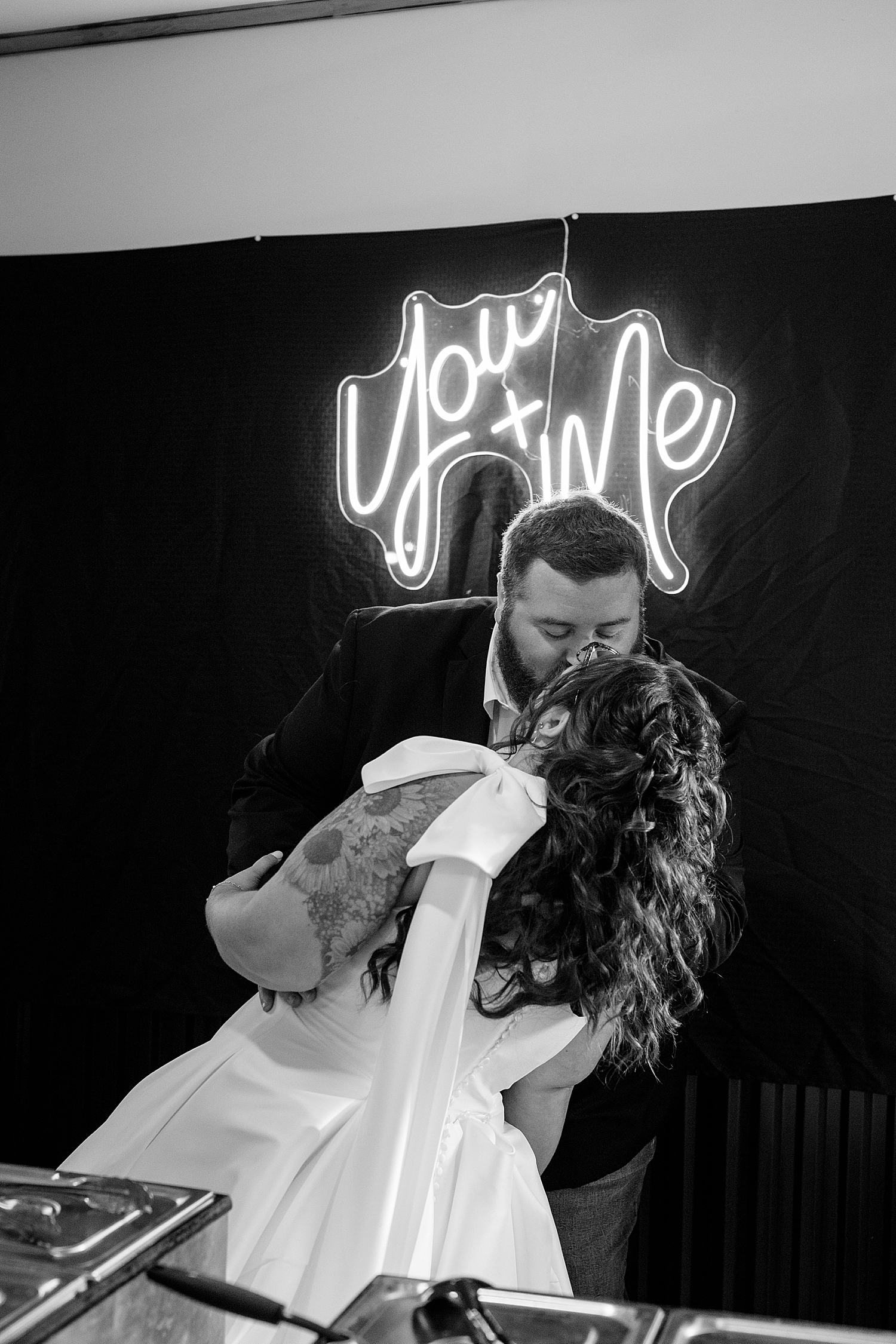 man dips is new wife for kiss in front of neon sign by Rule Creative Co