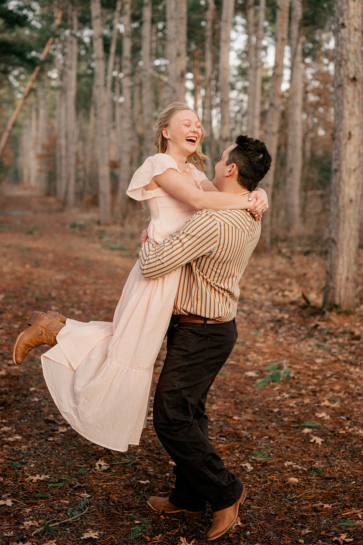 man lifts up his fiance and twirls her around in Bend in the River regional park by Minnesota wedding photographer