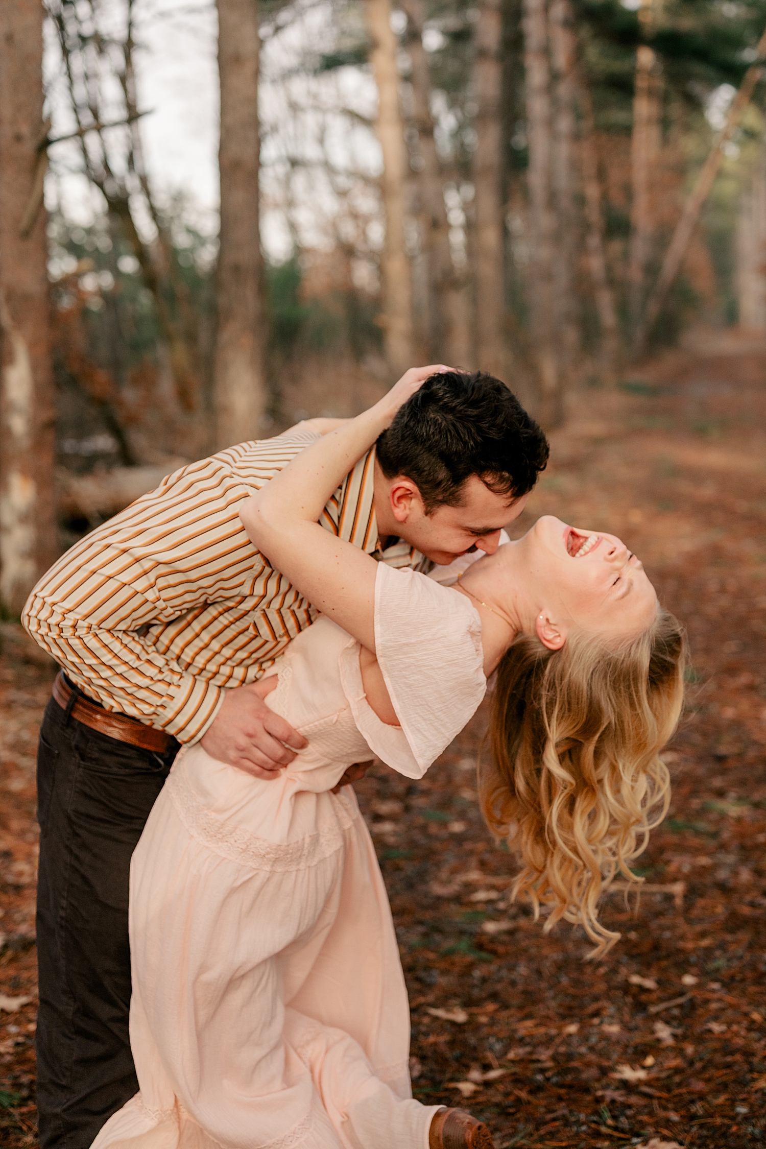 woman throws her head back laughing during playful engagement photos