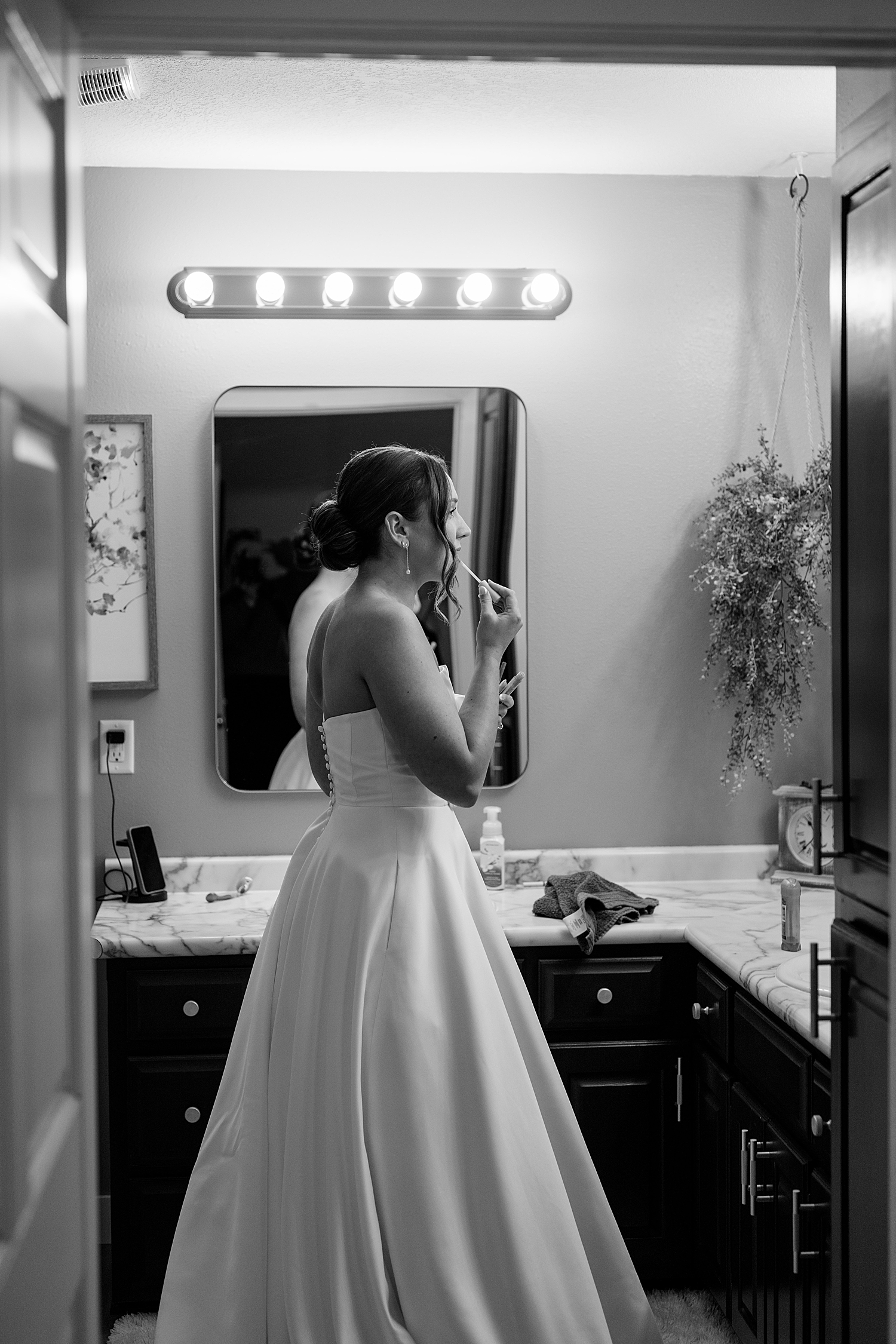 bride applies lipstick in the bathroom by MN elopement photographer