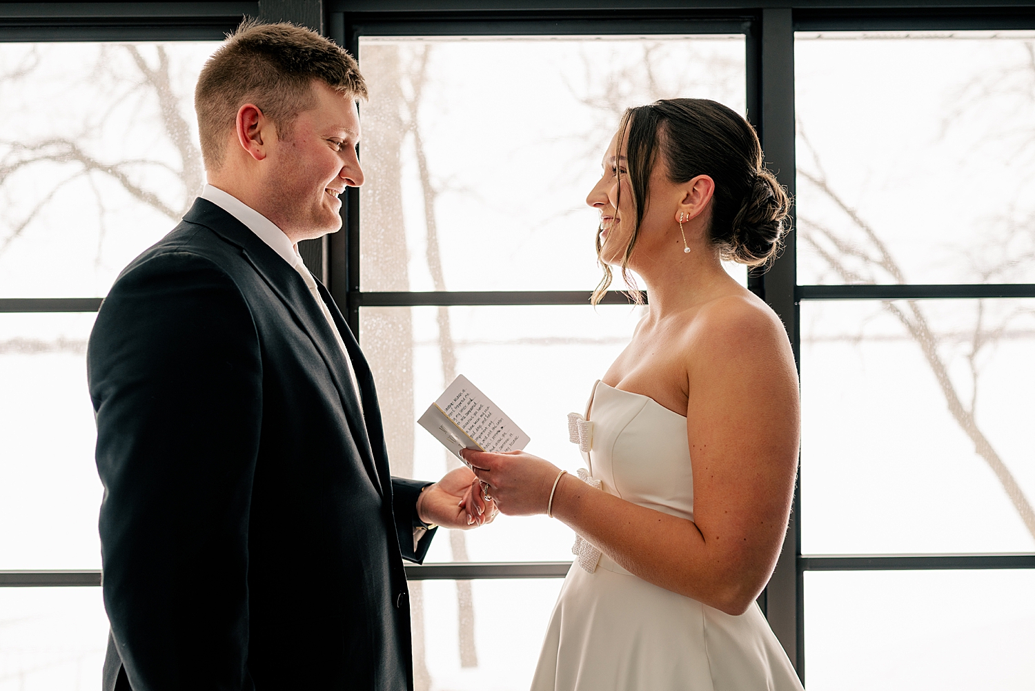 couple shares private vows in front of a window for Wintry Minnesota Wedding