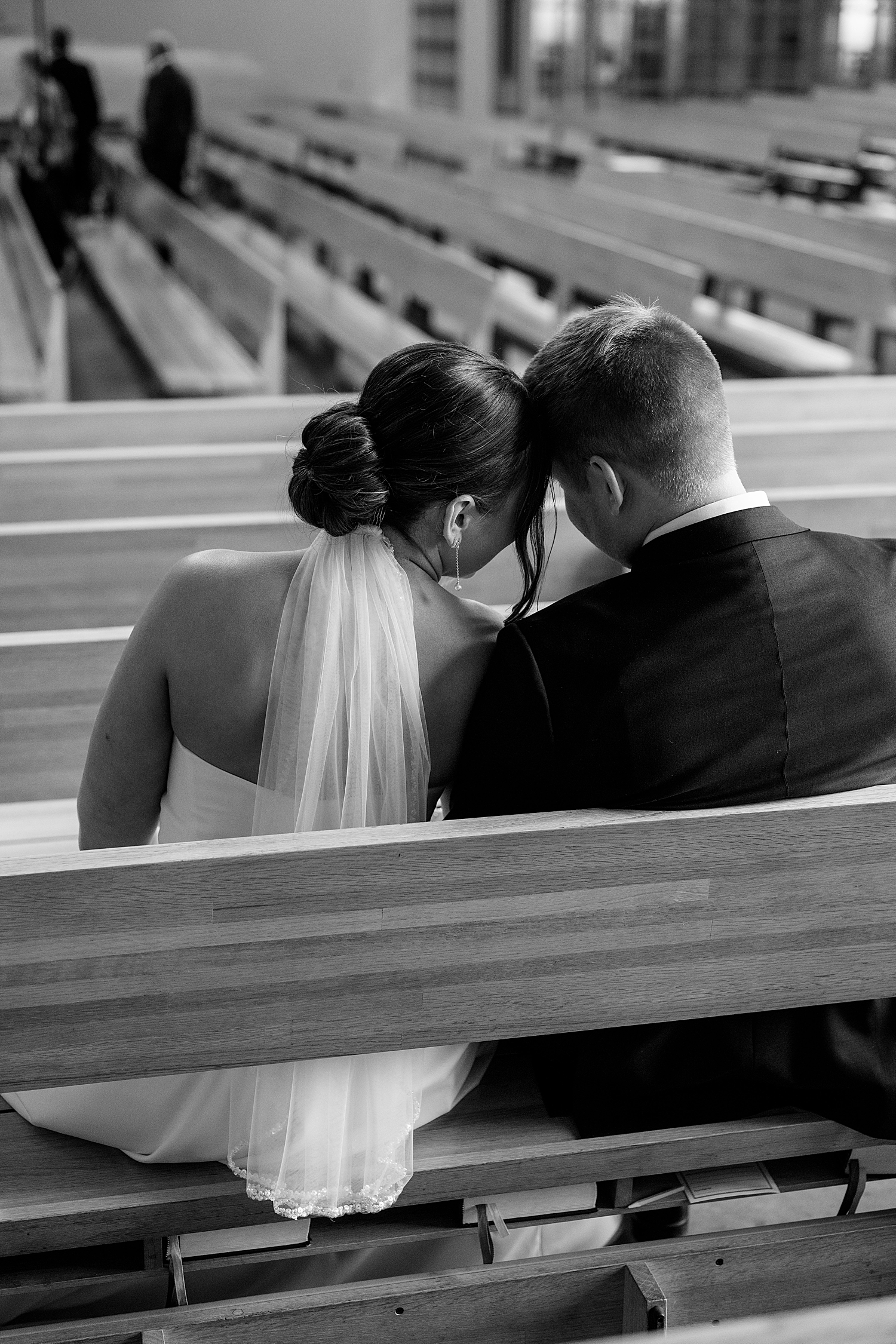 couple puts foreheads sitting in pew for Wintry Minnesota Wedding