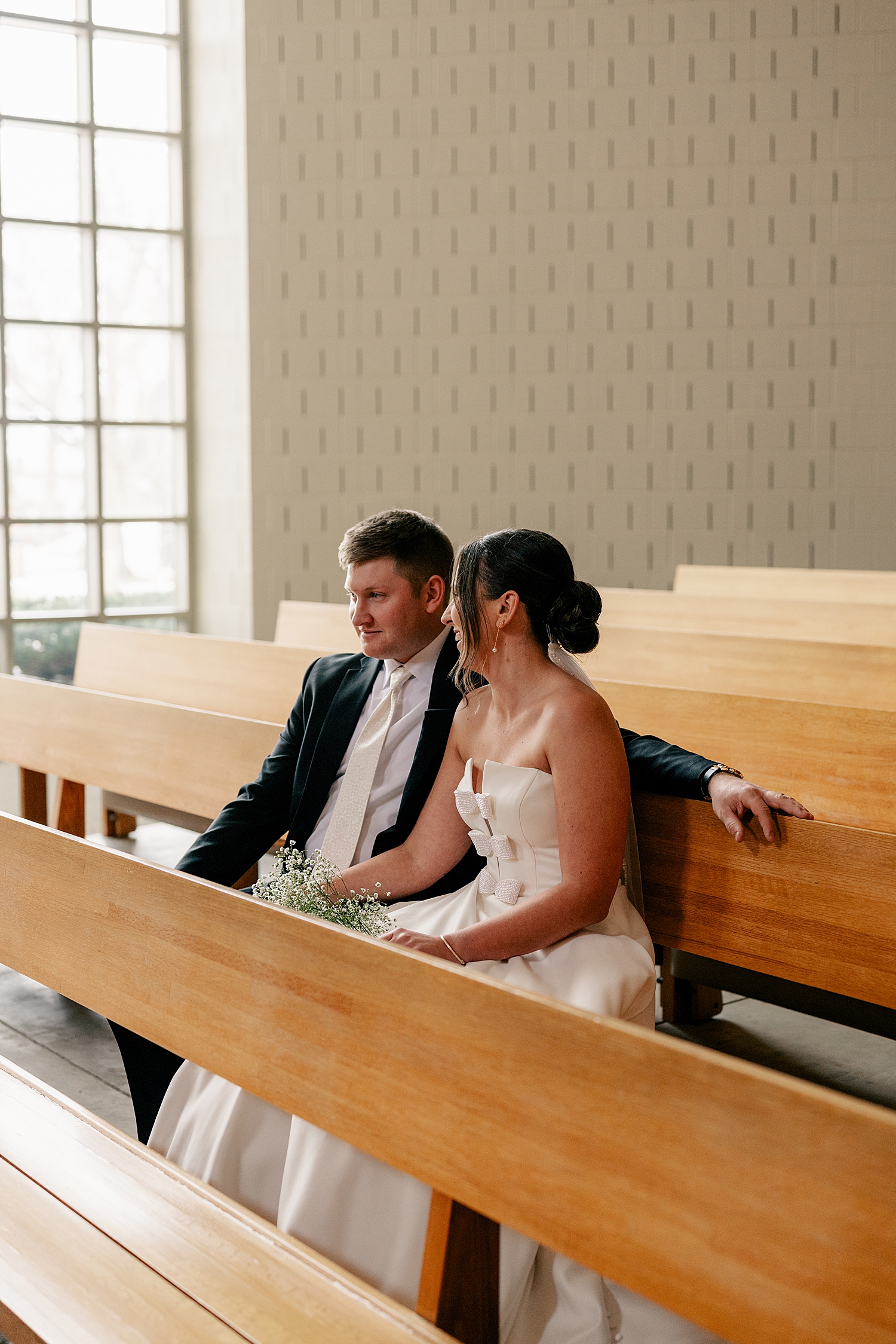 husband and wife sit together in the pews by MN elopement photographer