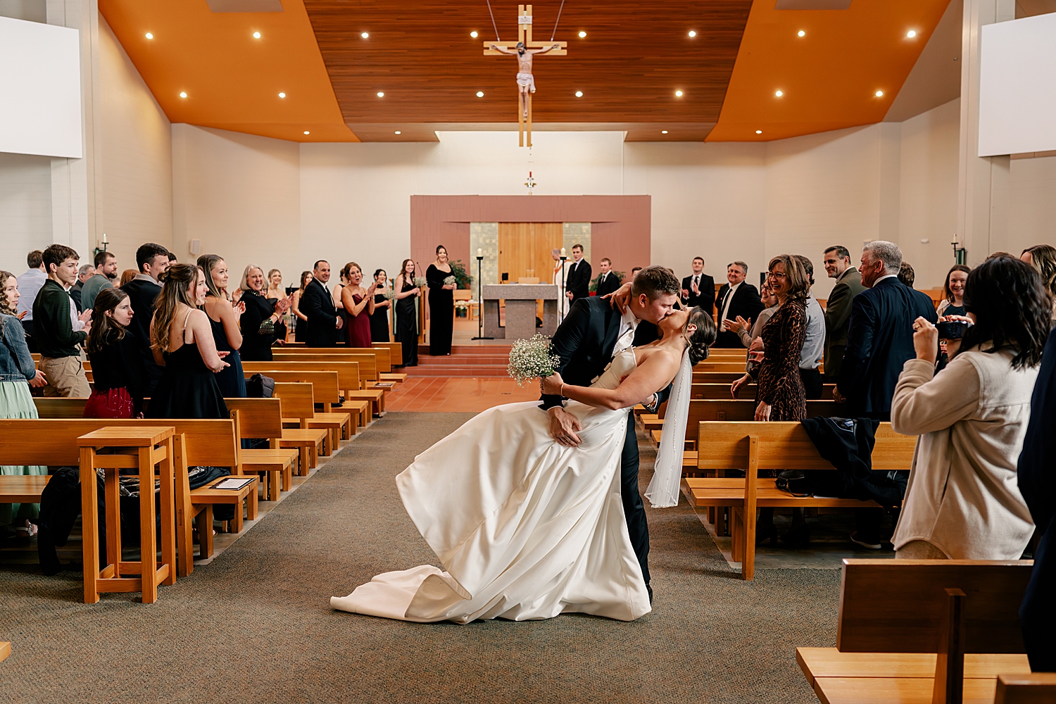man dips his new wife for a kiss at the end of the aisle by Rule Creative Co