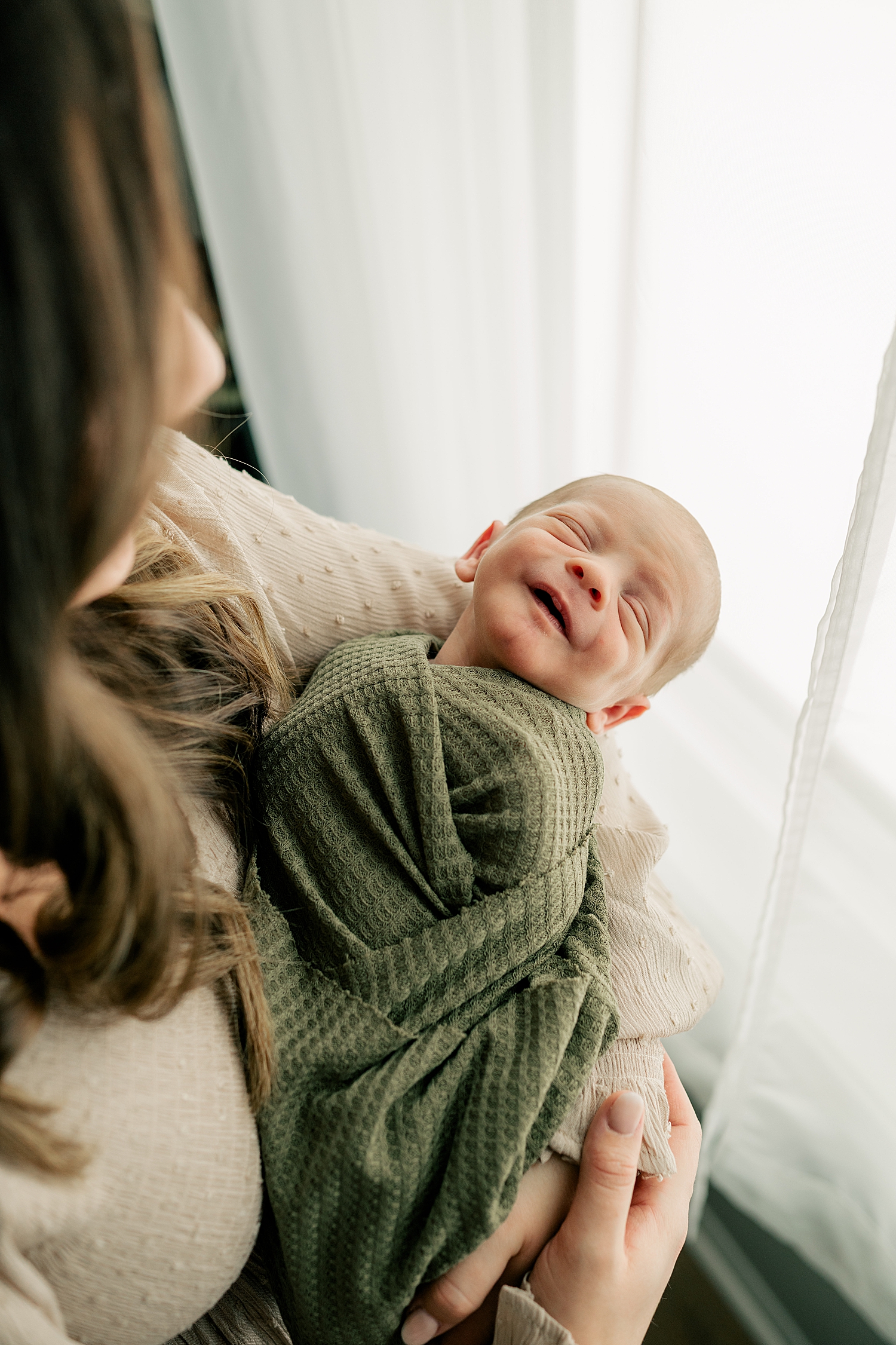 little one wrapped in green cloth by window for in-home session