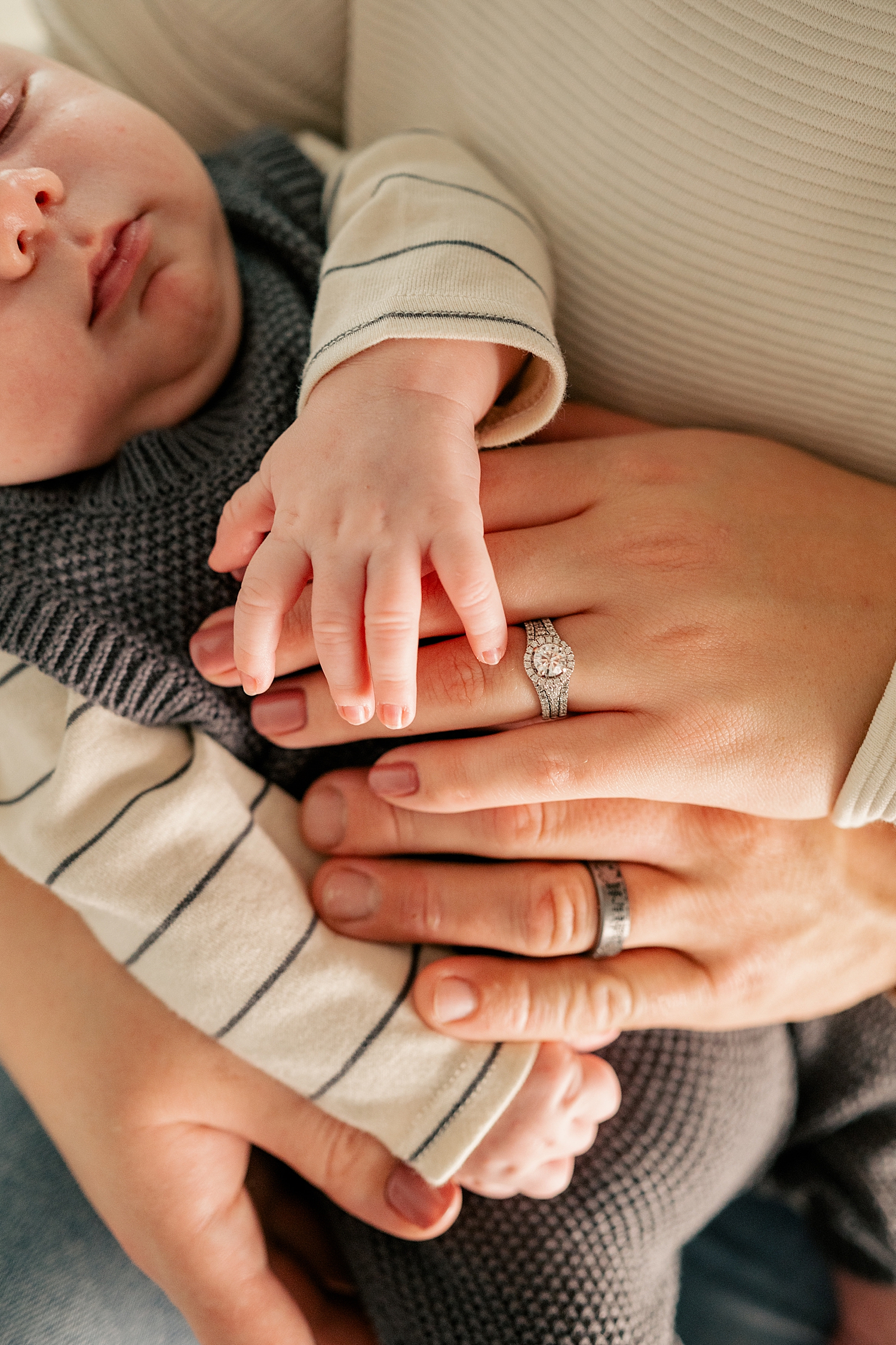 two hands with rings placed over infant for in-home session