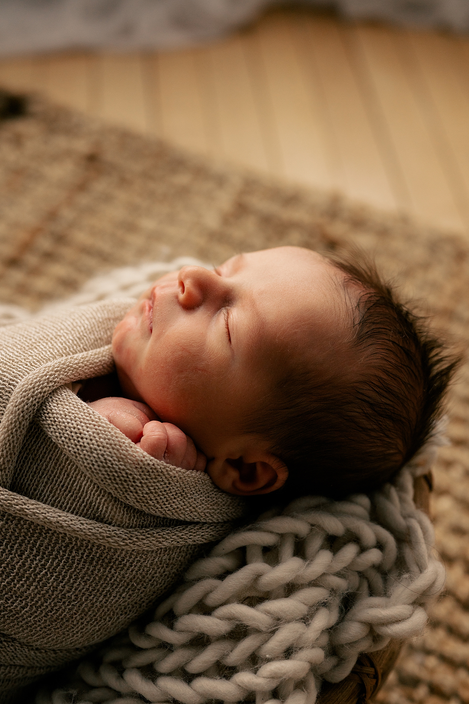 tiny baby with black hair wrapped in blanket by Rule Creative Co