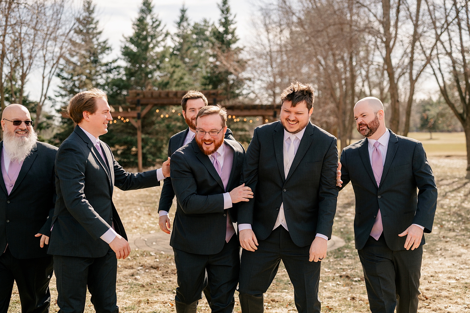 groom surrounded by groomsmen outside by MN Elopement Photographer