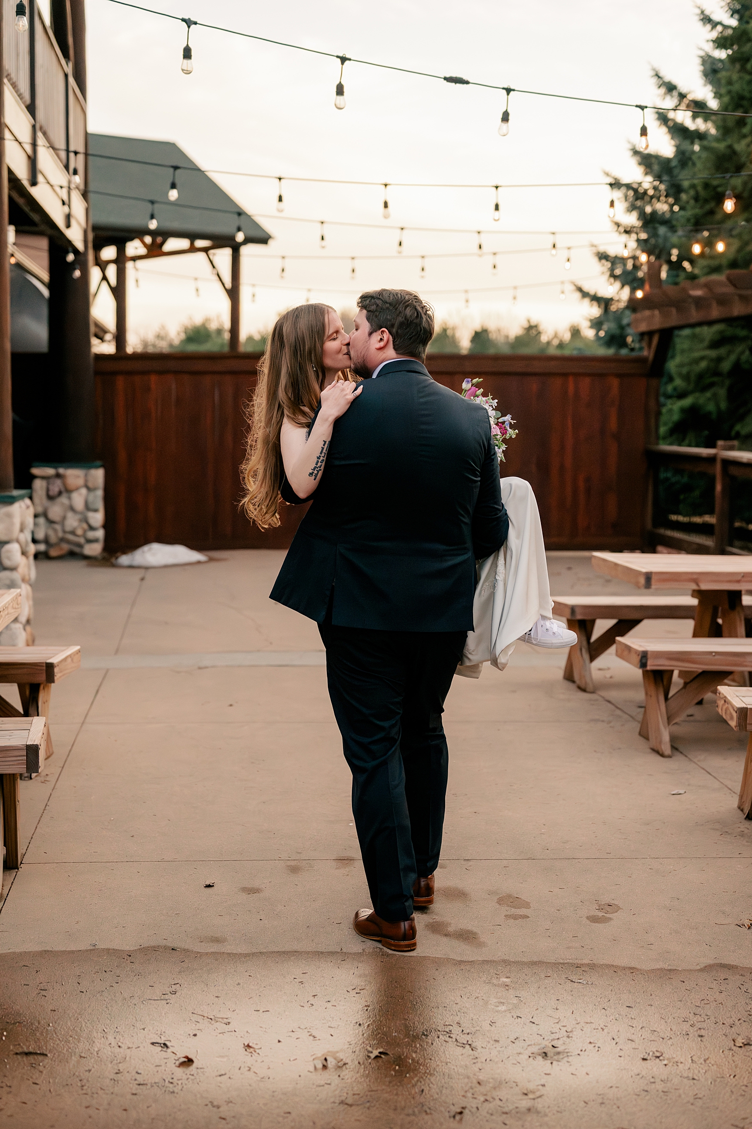 groom carries his bride across patio for Minnesota Spring Wedding