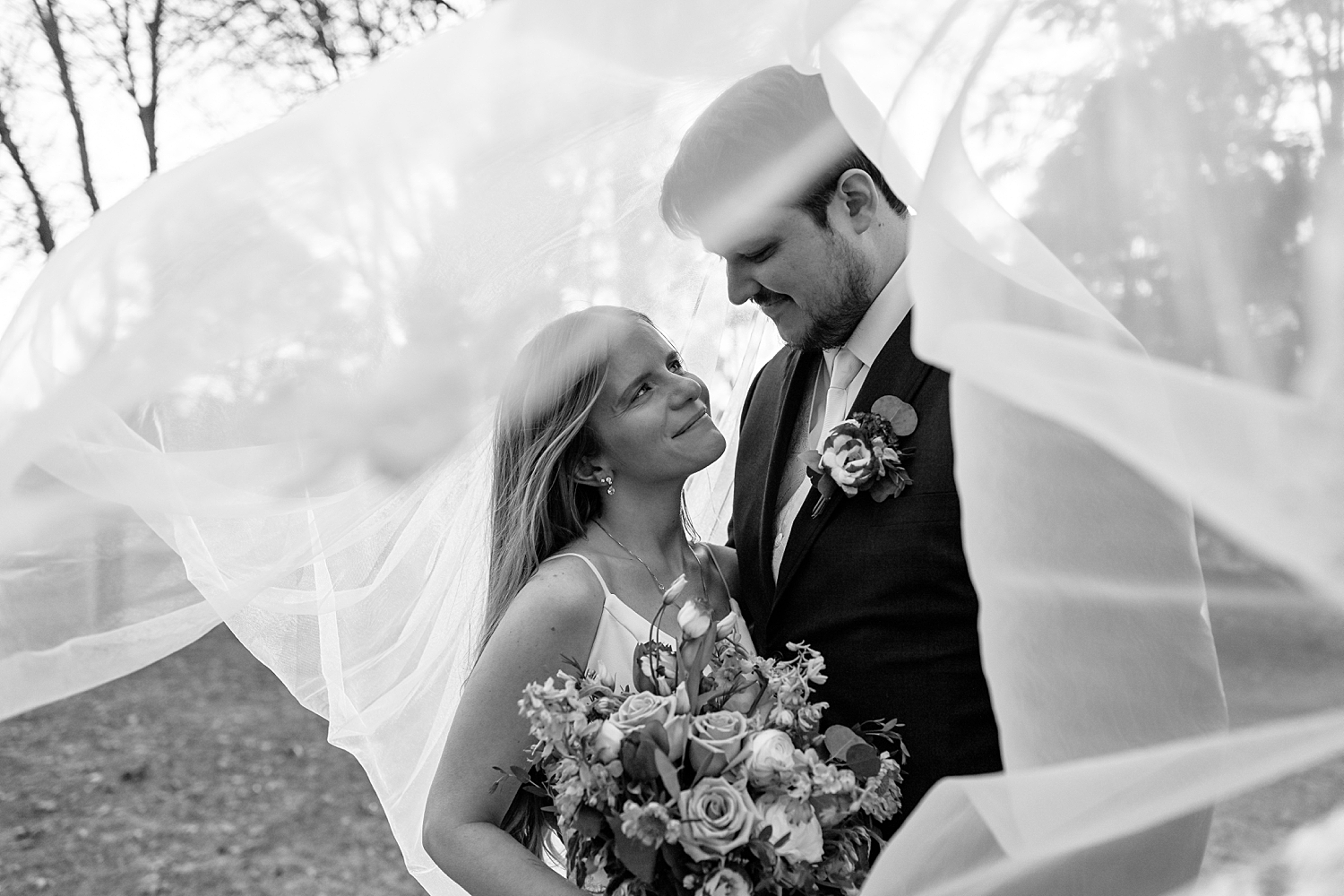bride gazes up with love at her groom under veil for Minnesota Spring Wedding