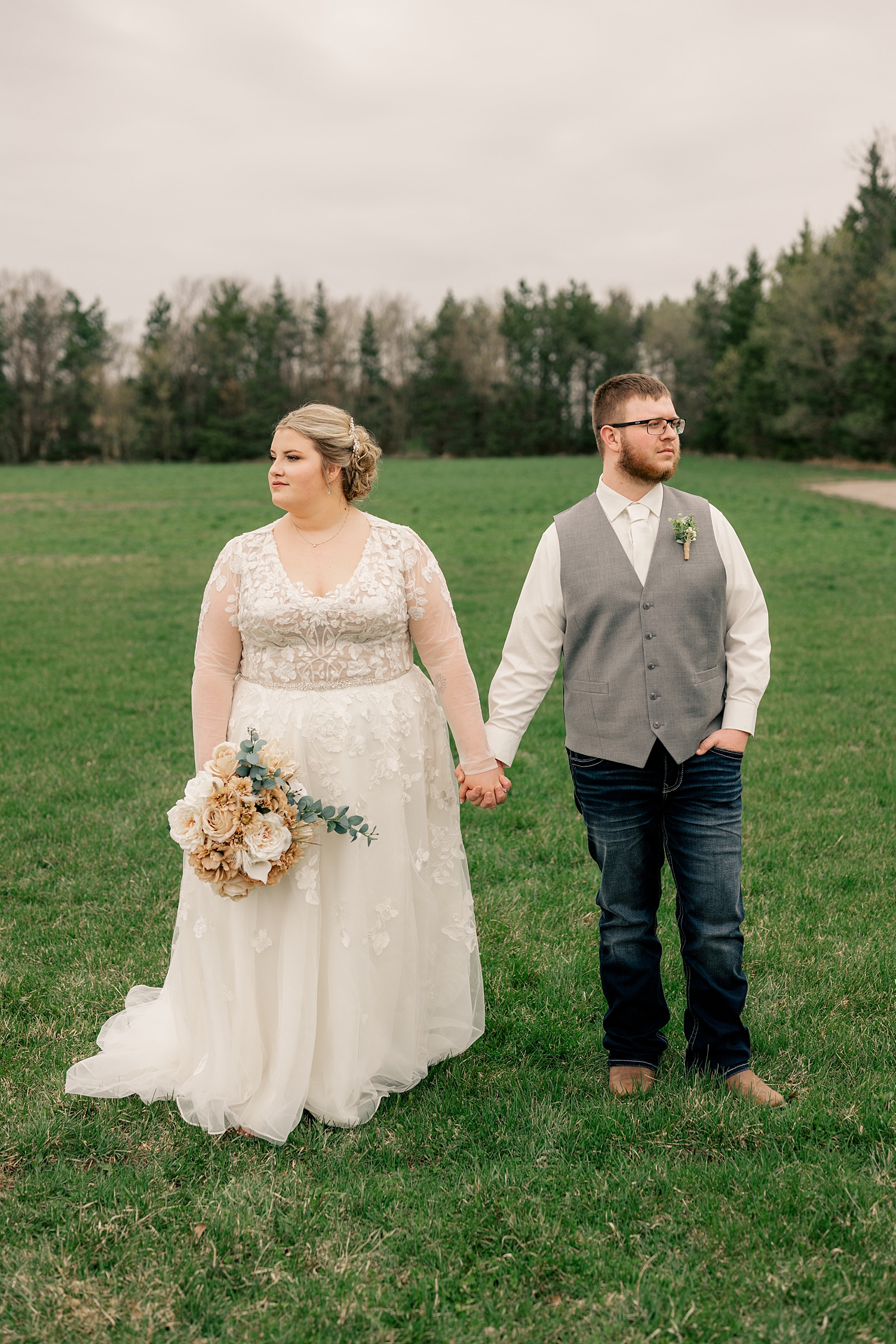 couple holds hands in field looking opposite directions by Rule Creative Co
