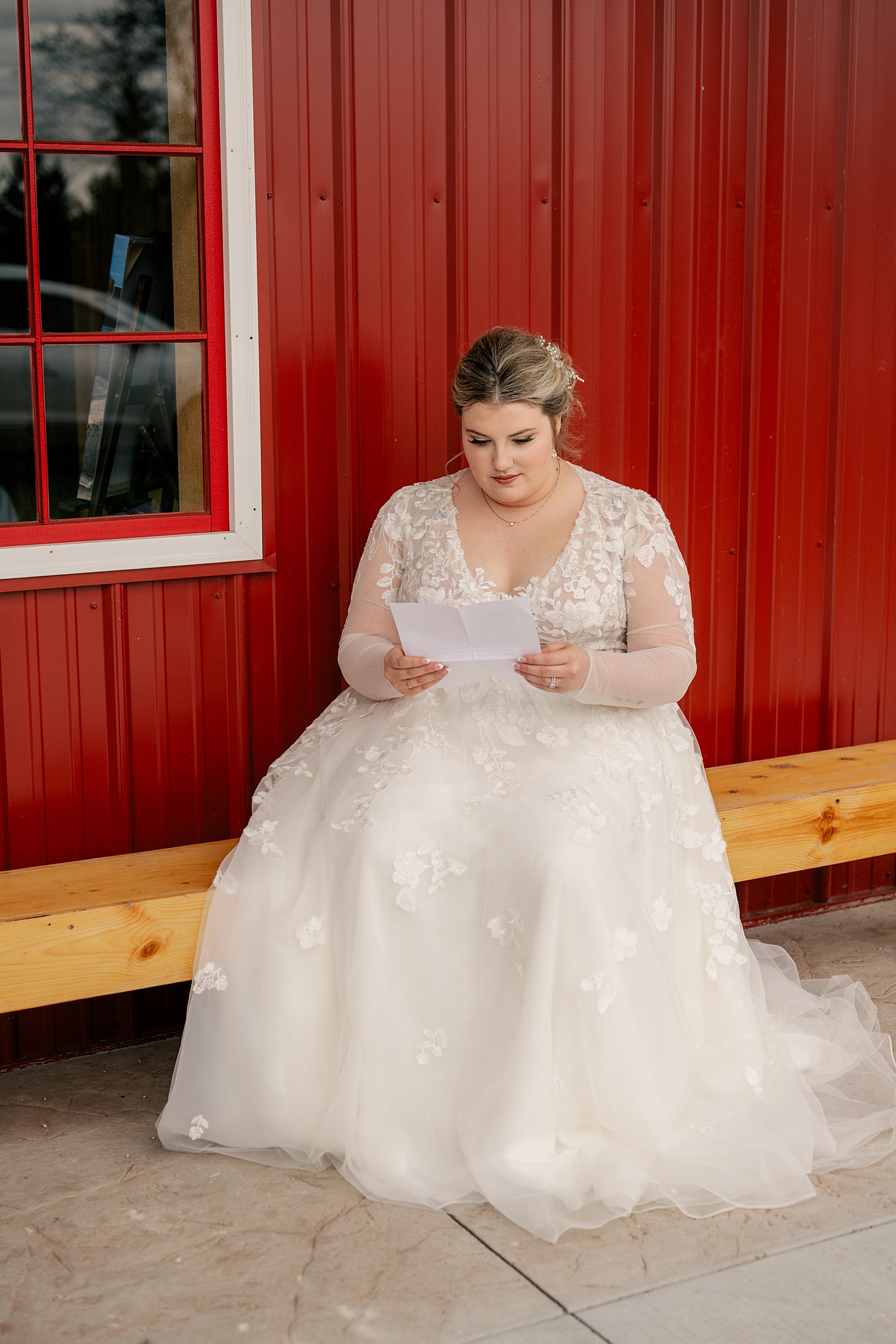 bride reads private note next to red wall by Minnesota wedding photographer