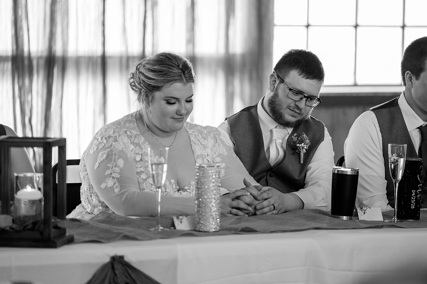 bride and groom bow their heads in prayer during cozy reception at The Hayshed