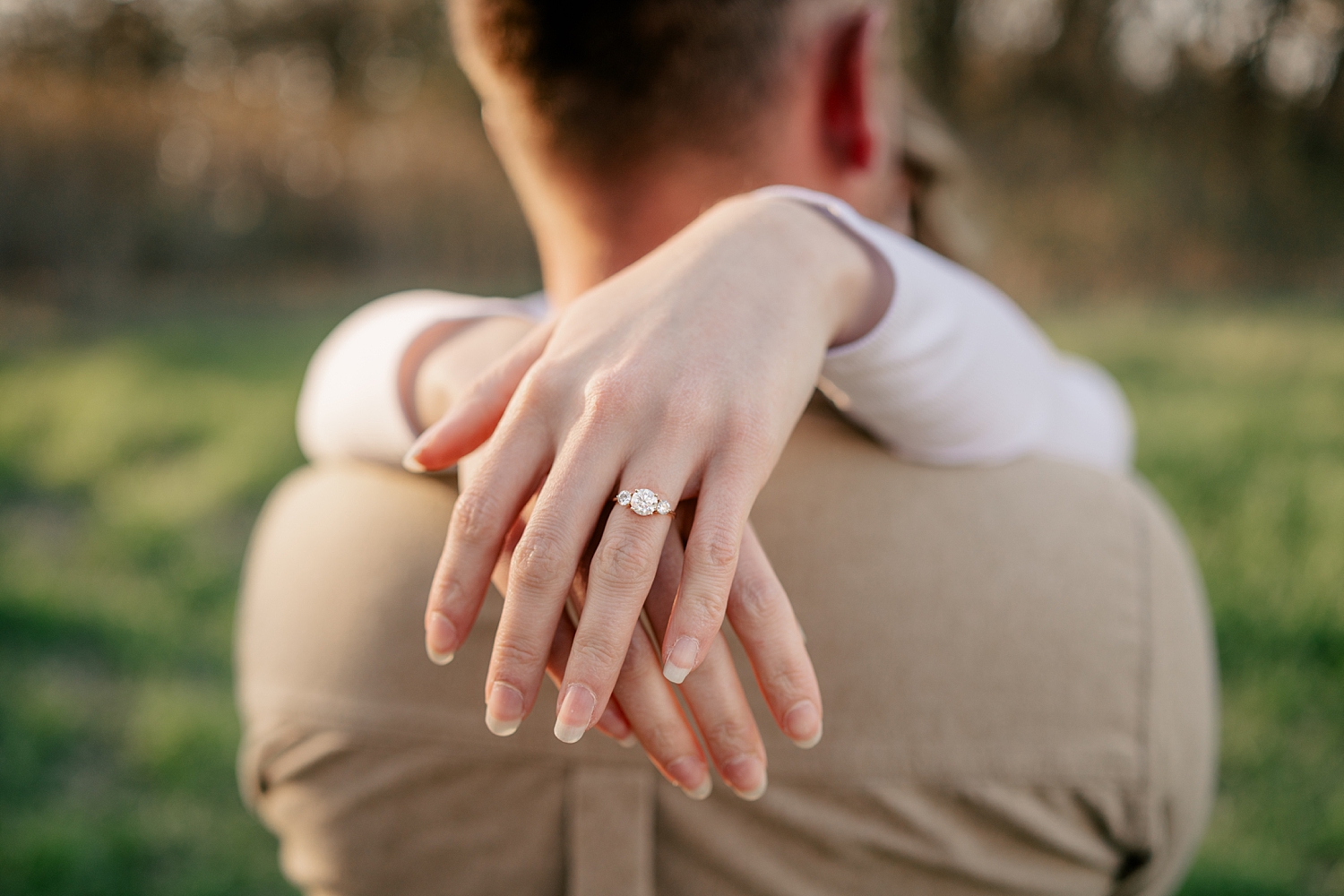 woman shows off her diamond ring while hugging her man by Minnesota wedding photographer