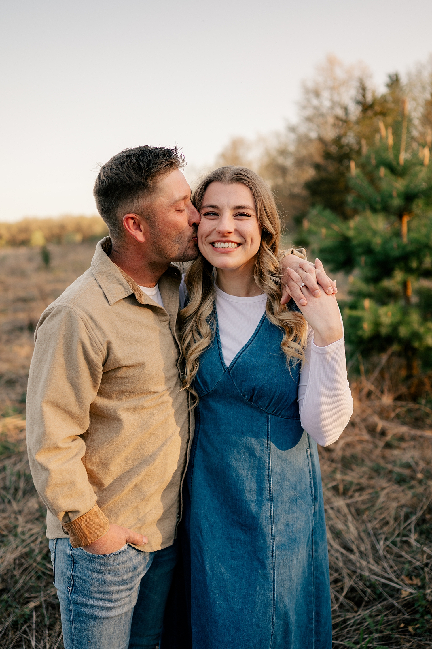 man leans in to kiss his woman at Bend in The River Park for summer engagement photos