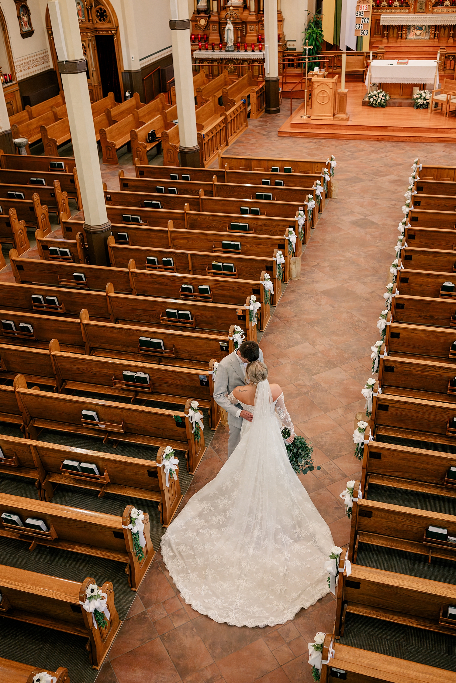 newlyweds stand in empty aisle hugging by Minnesota wedding photographer