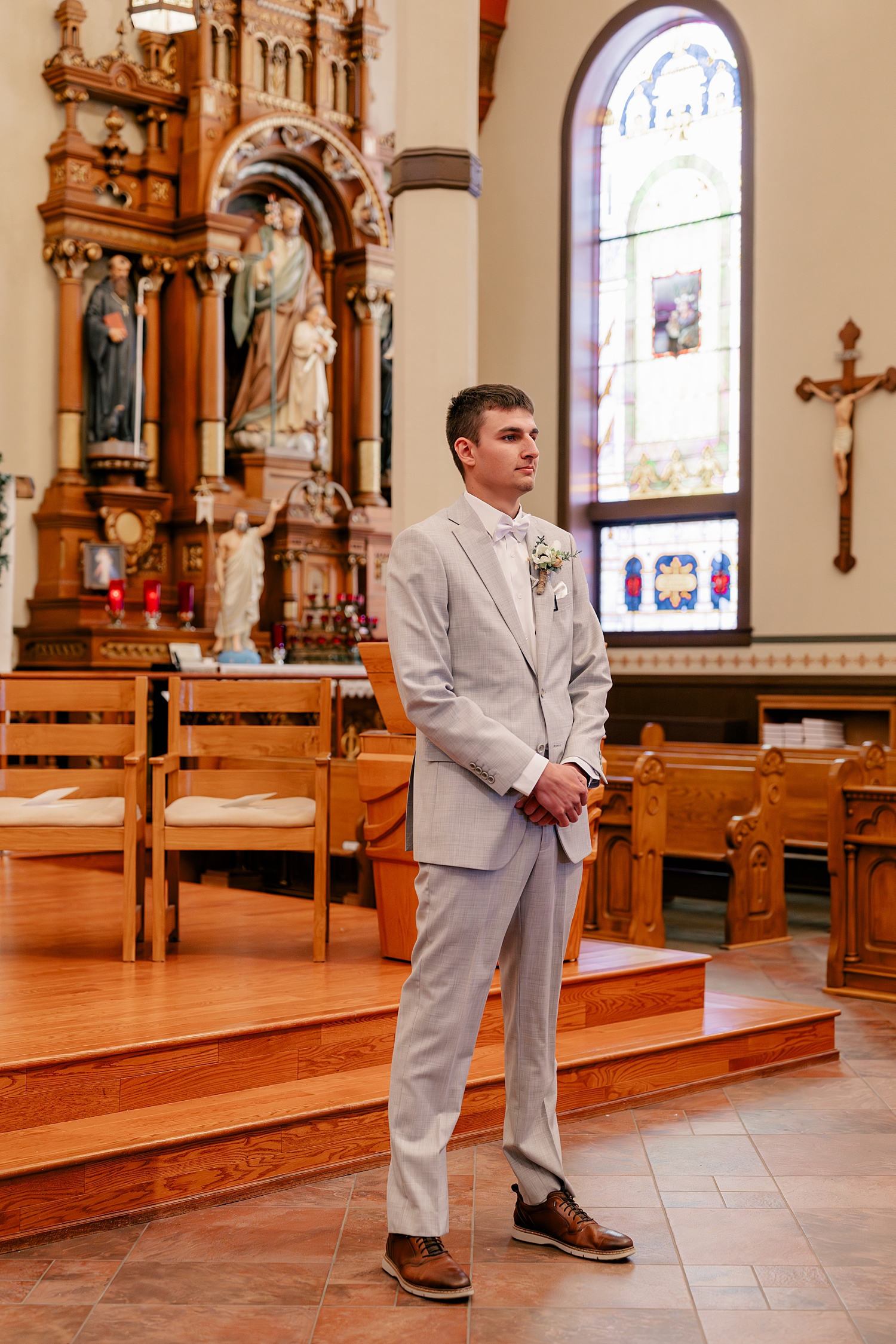 groom stands at alter in church before reception at Stearns County Pioneer Club