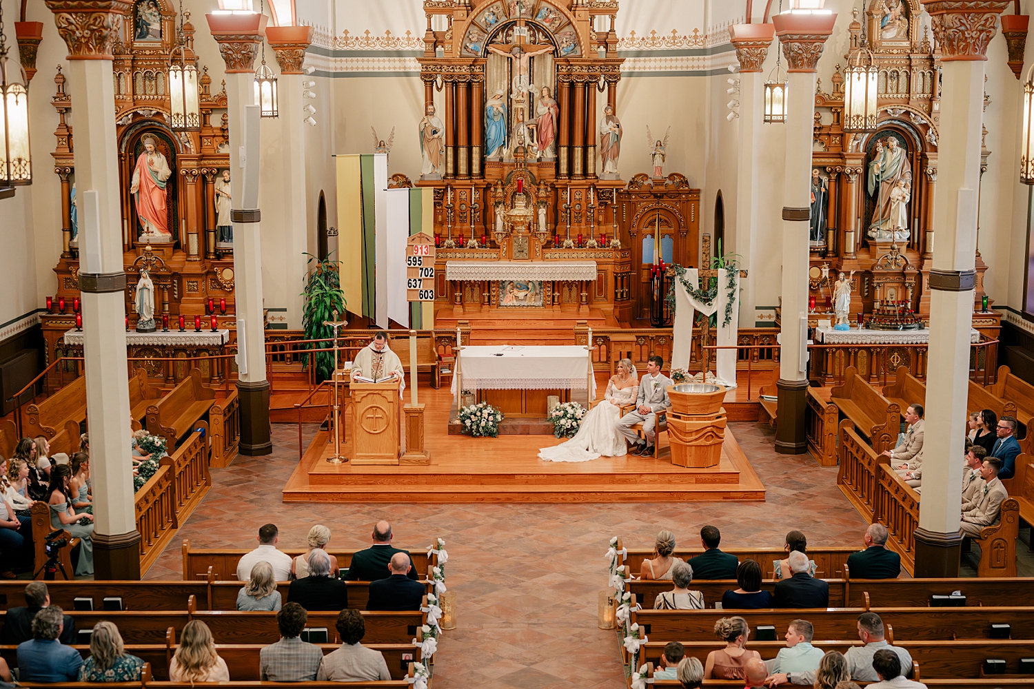 couple sits down on alter during catholic ceremony by Rule Creative Co 