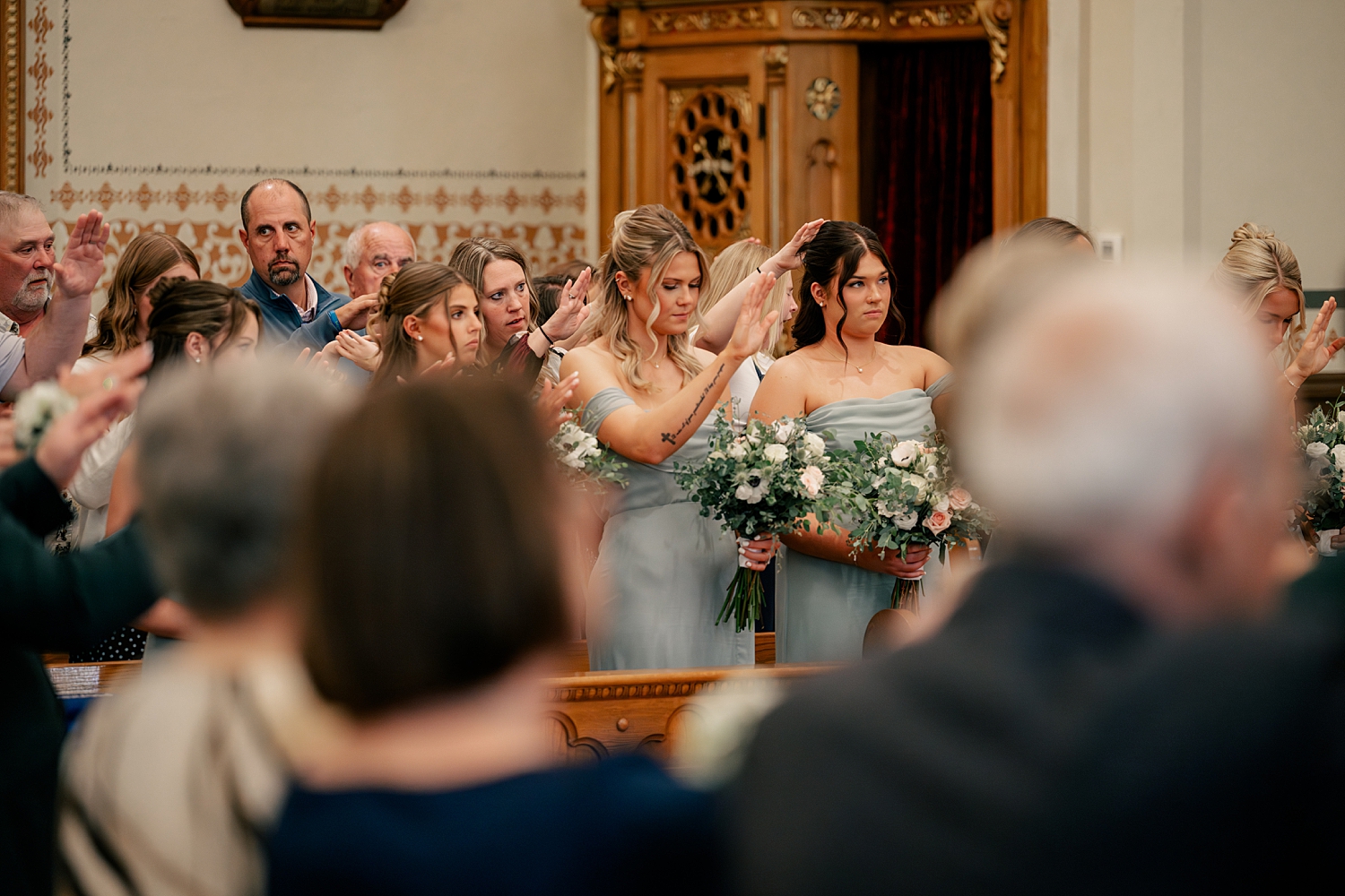 bridesmaids pray over couple during ceremony by Minnesota wedding photographer