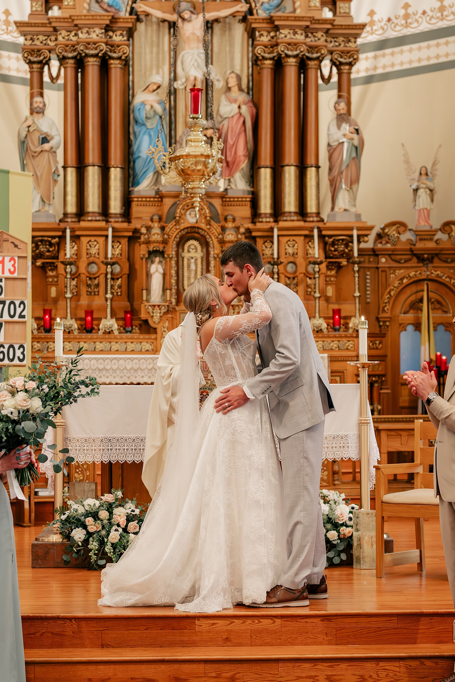 newlyweds share their first kiss at catholic alter by Rule Creative Co 