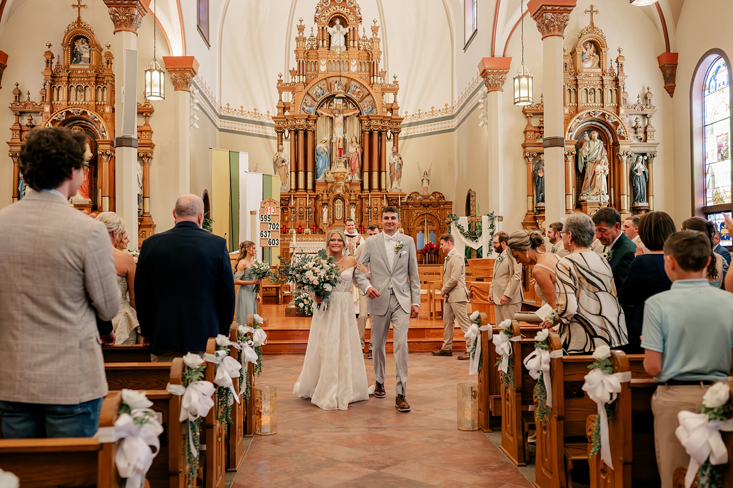 newlyweds walk down the aisle at church before reception at Stearns County Pioneer Club
