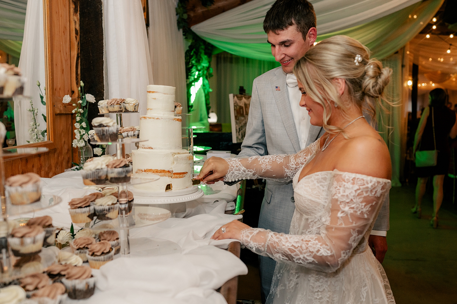 newlyweds cut a naked frosted three tier cake by Minnesota wedding photographer