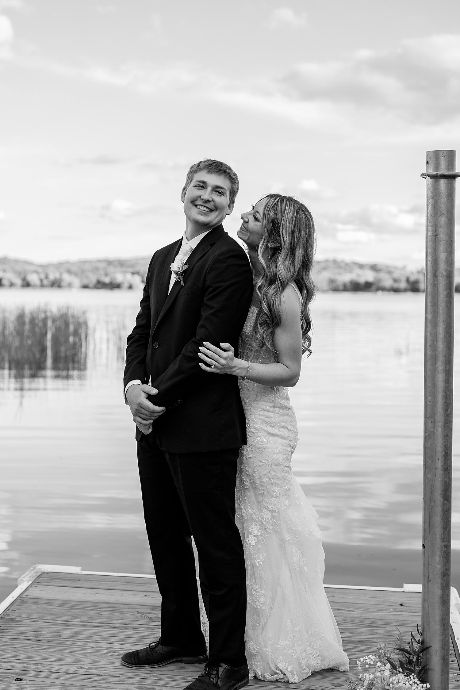 new wife grins up at her husband on a dock by Minnesota wedding photographer 