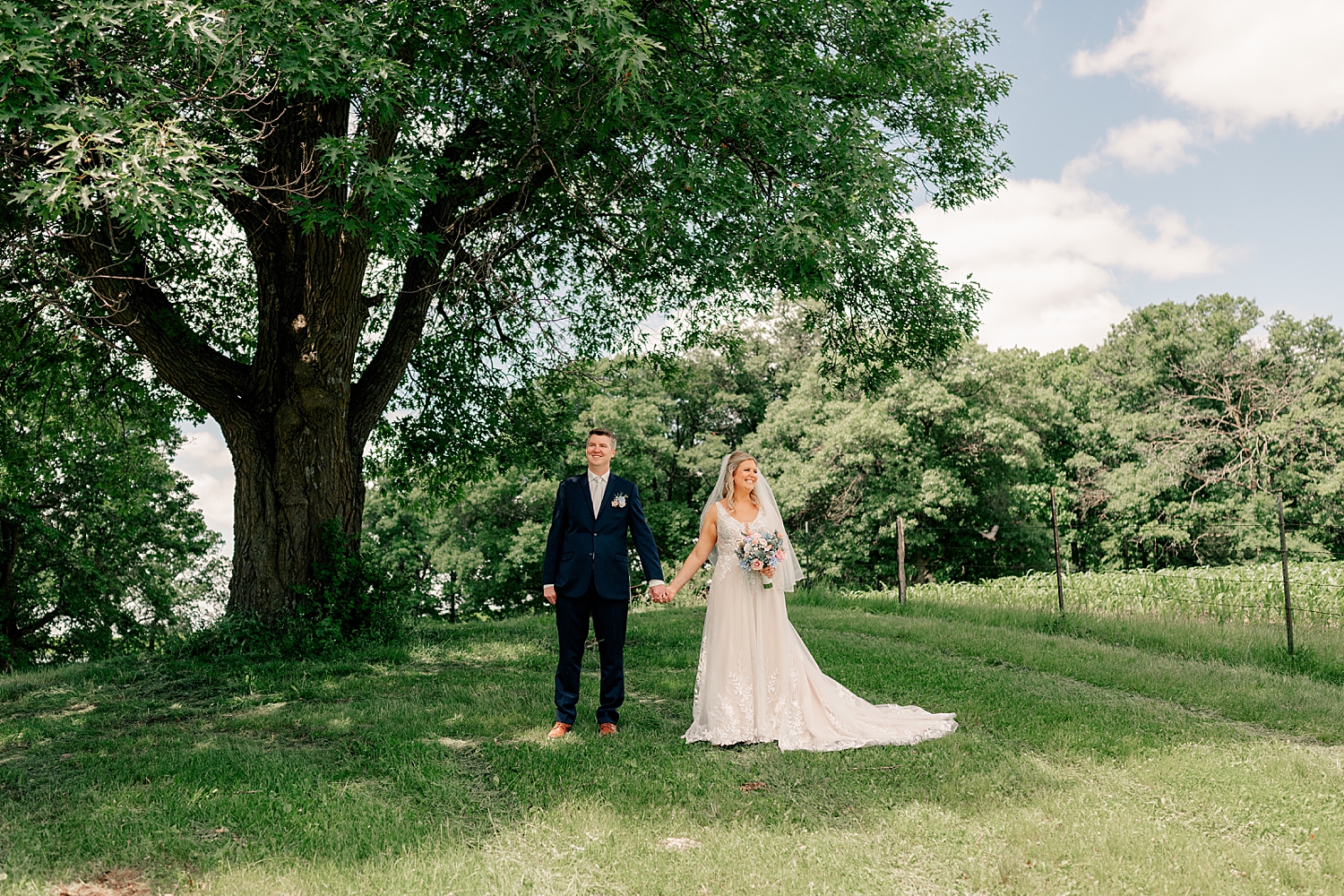 couple stand under big tree by Minnesota wedding photographer 