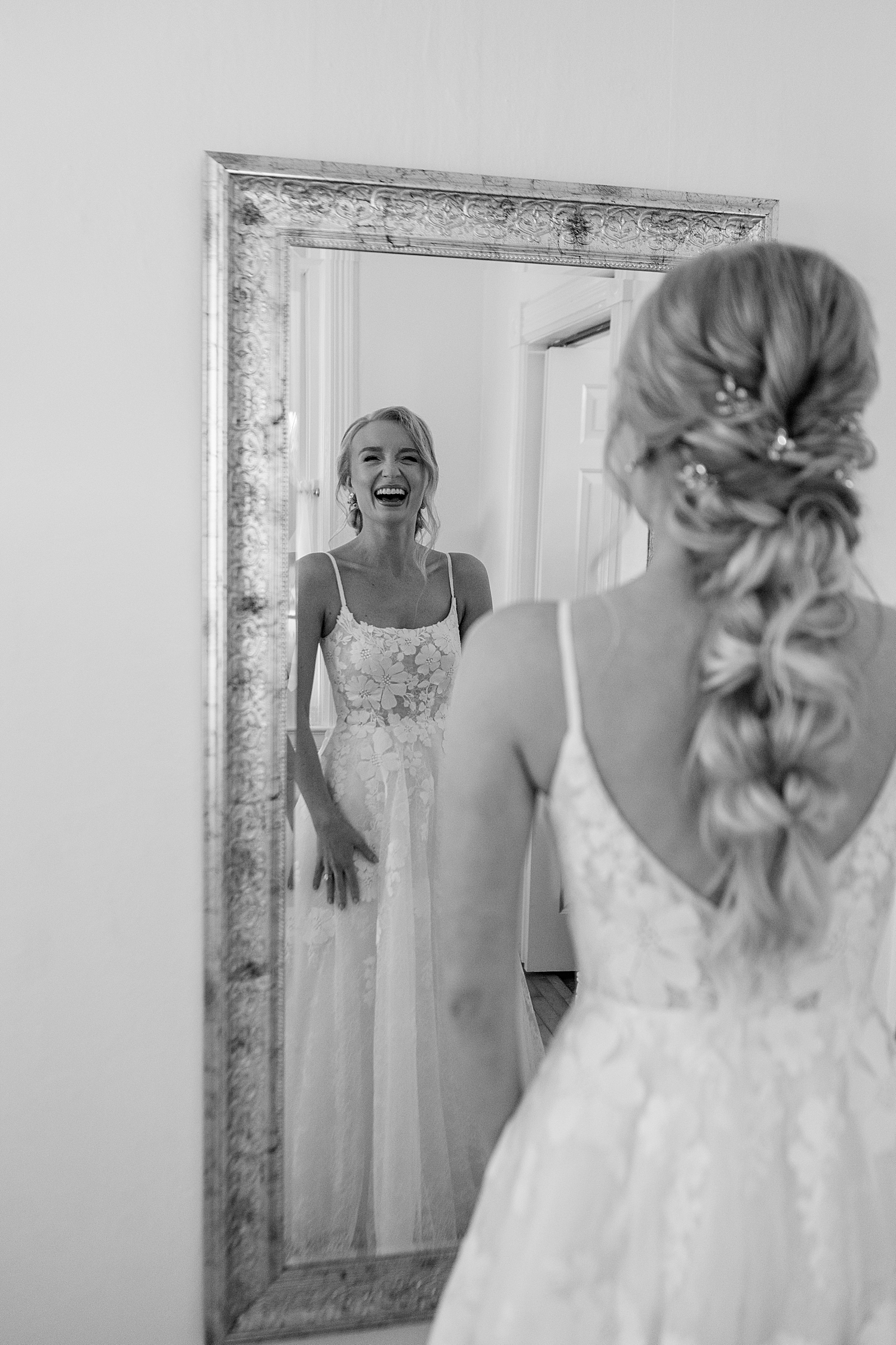bride giggles in the mirror seeing her gown at Abella Weddings and Events