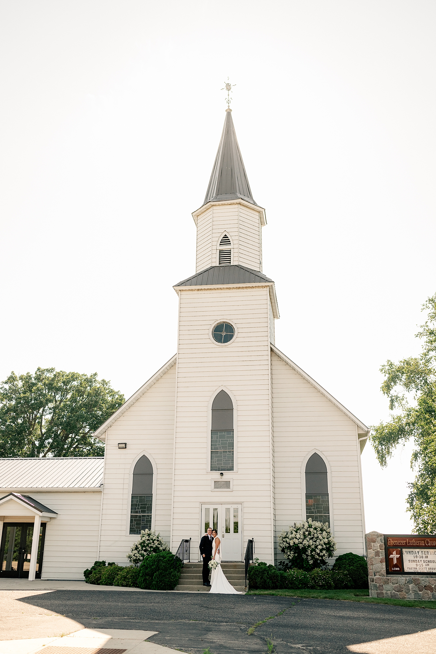 couple stand in front of their ceremony church before backyard elopement in Minnesota