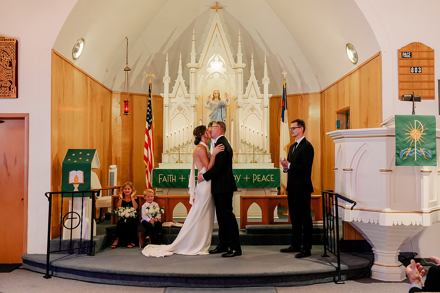 newlyweds share their first kiss at Catholic church alter by Rule Creative Co