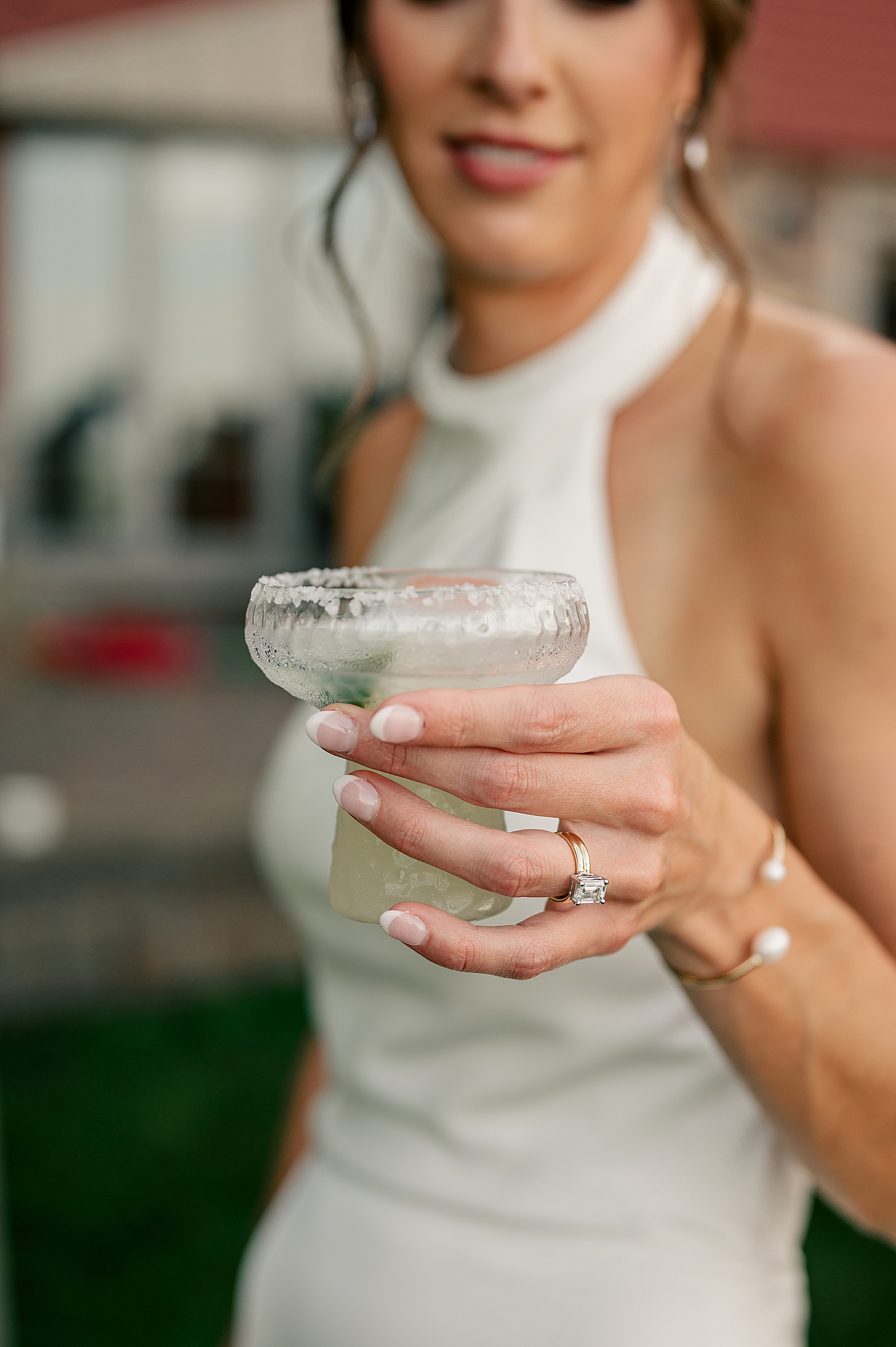 bride holds up a cocktail and shows her new ring by Rule Creative Co