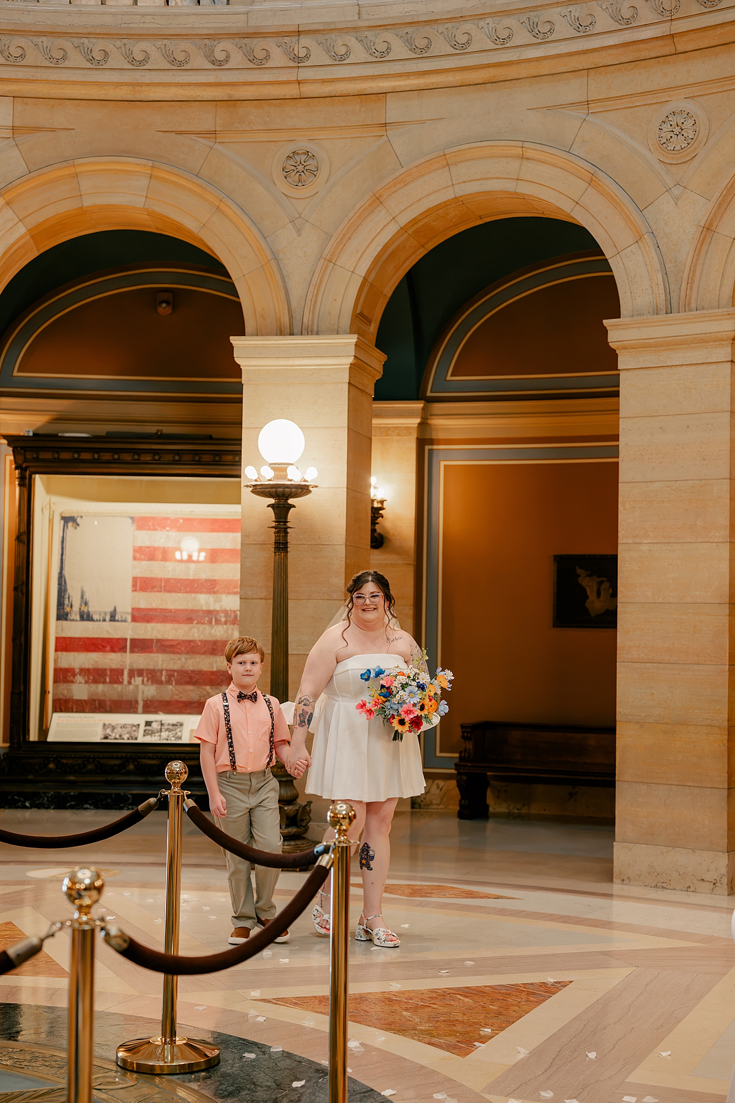 brunette bride walks in with son on her arm for State Capitol Building Elopement