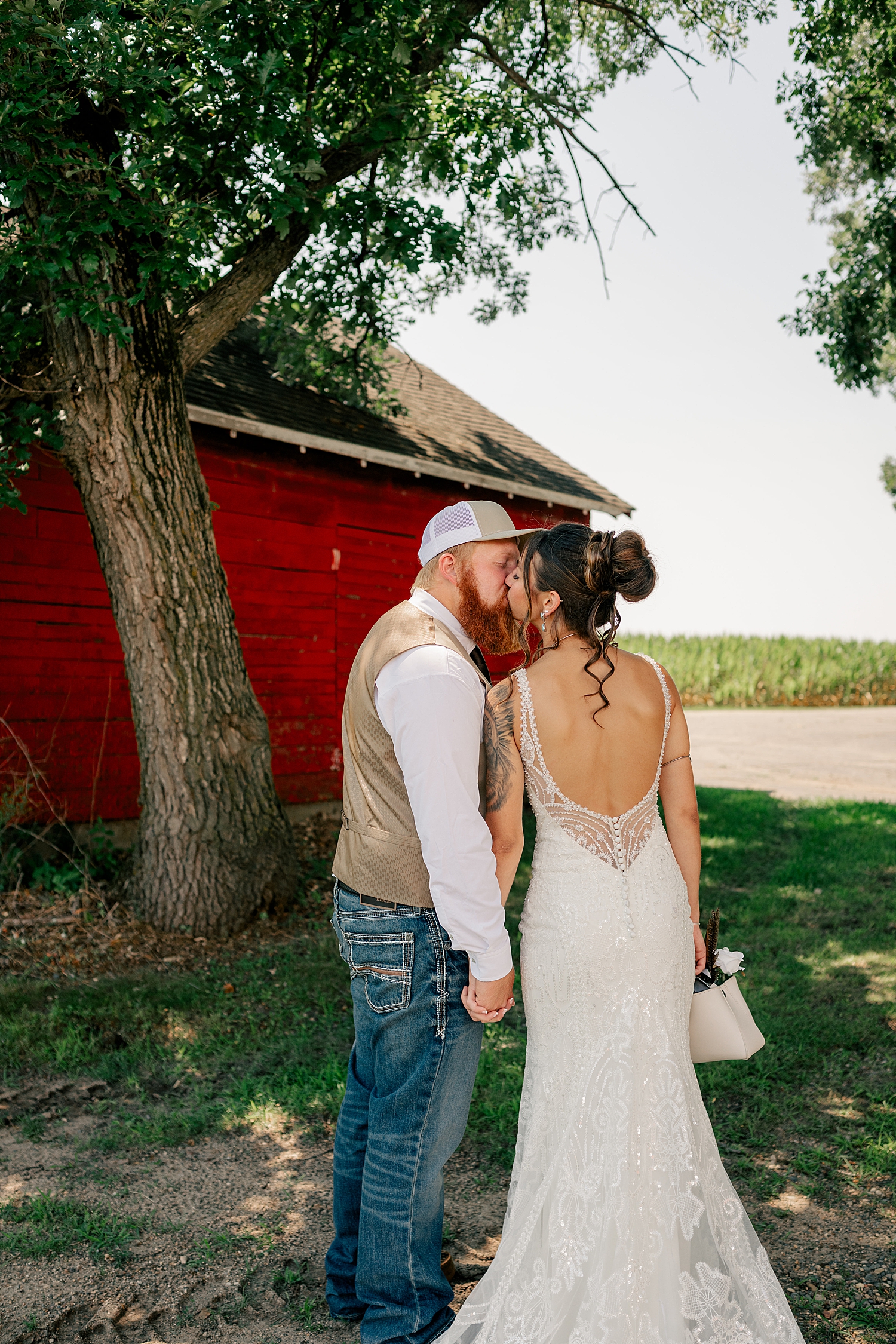 Newlyweds kiss under tree for red barn wedding