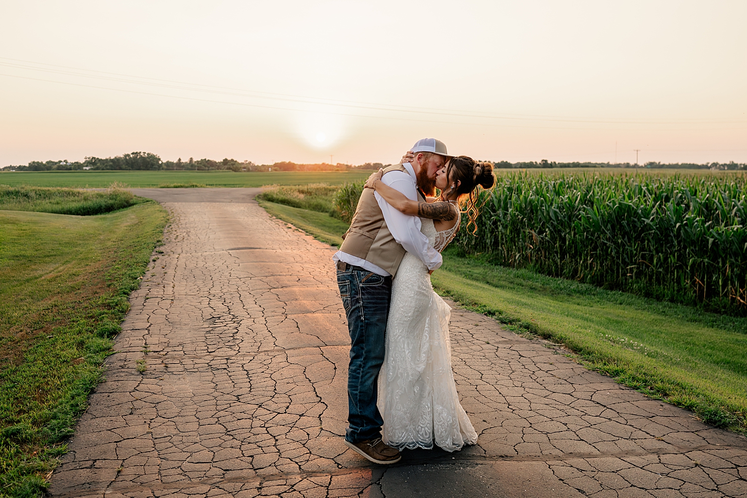 newlyweds kiss on old country road at golden hour by Minnesota wedding photographer