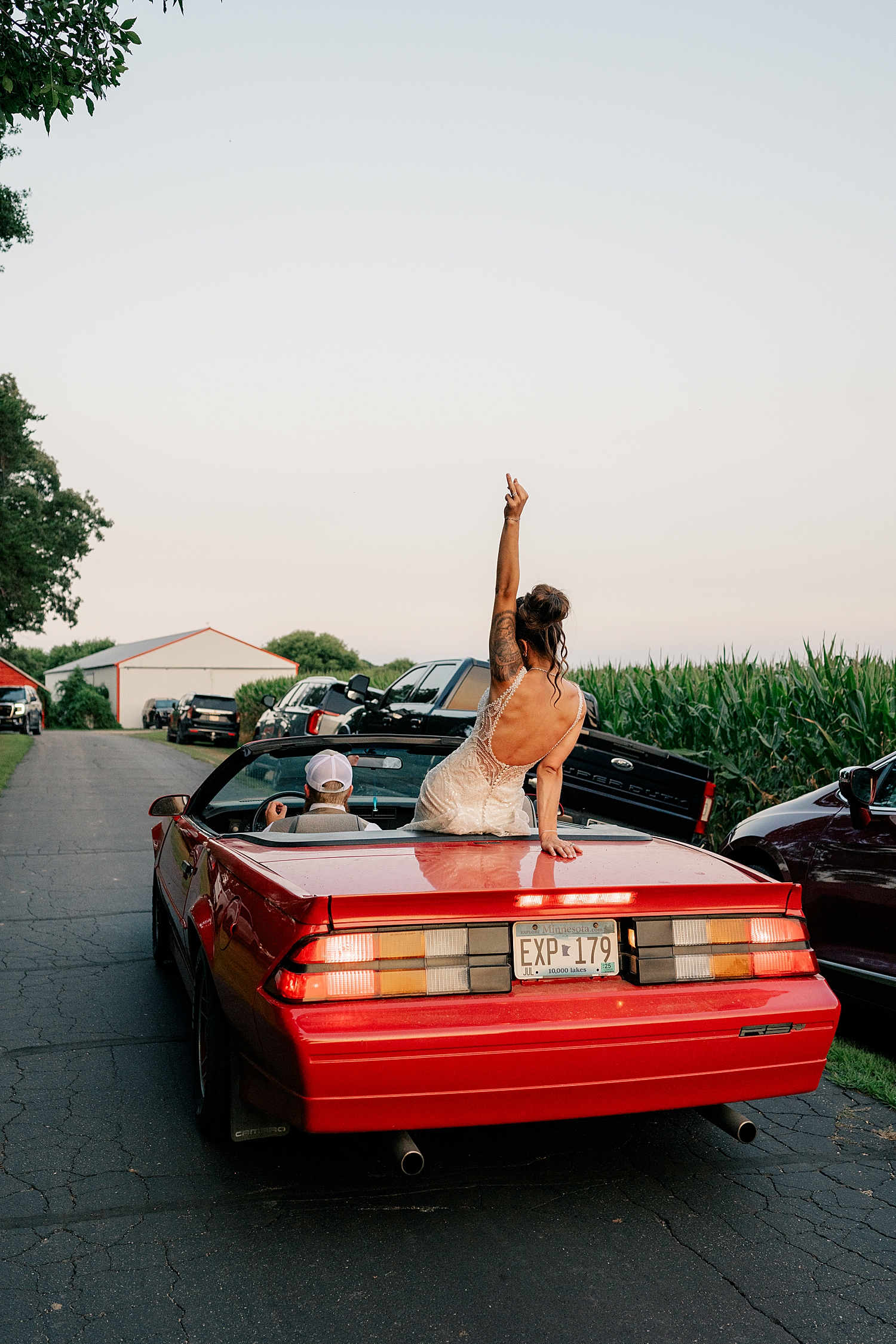bride sits on back of red convertible by Minnesota wedding photographer