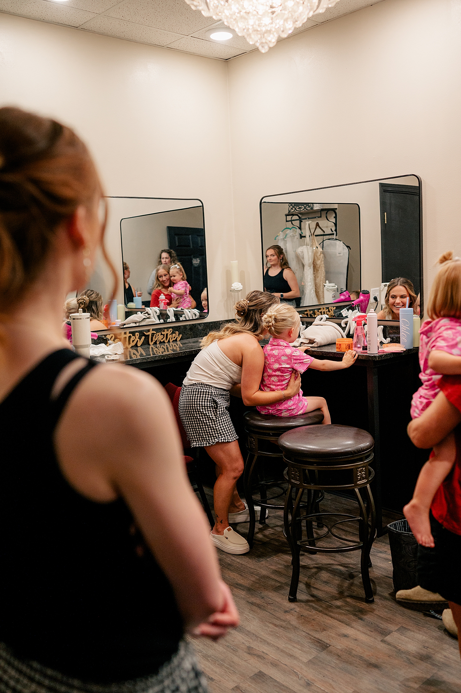 bride holds girl in pink pajamas on makeup stool by Minnesota photographer